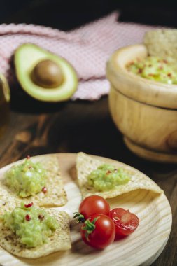 ahşap masa üzerinde guacamole ve avokado ile nachos
