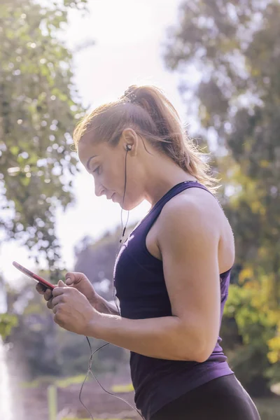 sports woman checking her phone app before running