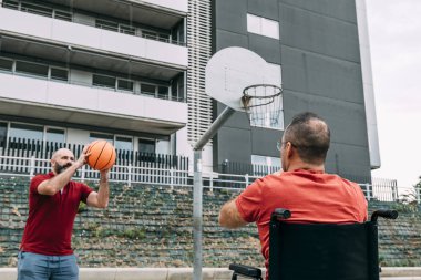 bir arkadaşı ile basketbol oynayan engelli adam