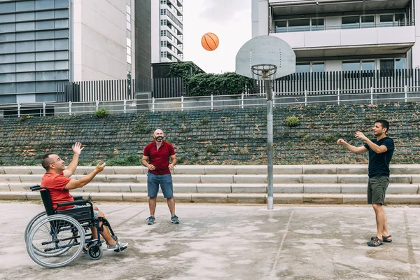 Człowiek na wózku inwalidzkim gra w koszykówkę z przyjaciółmi — Zdjęcie stockowe
