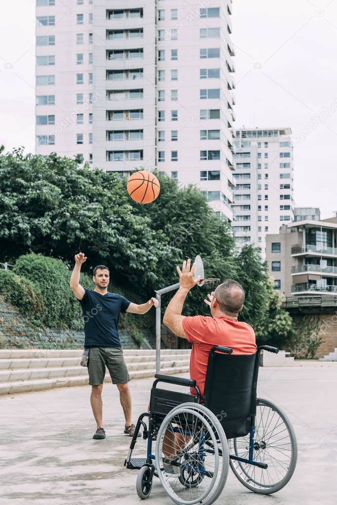 man in wheelchair playing basketball with a friend