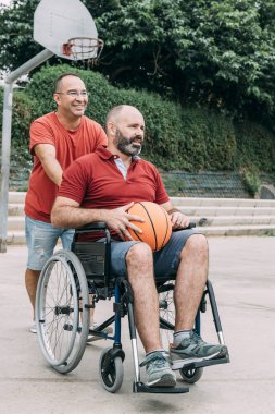 arkadaş basketbol oynamak için tekerlekli sandalye iter