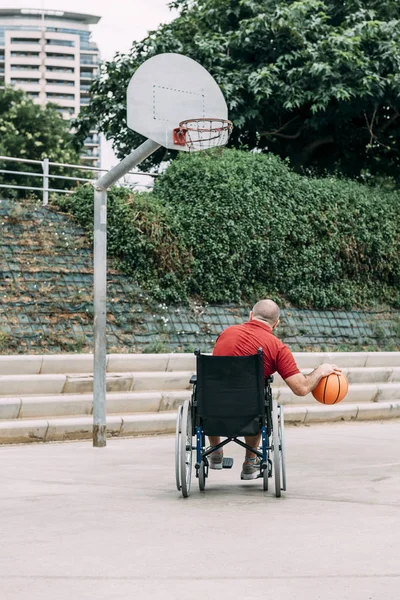 man in wheelchair playing basketball alone