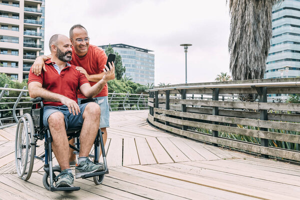 man in wheelchair taking a selfie with a friend