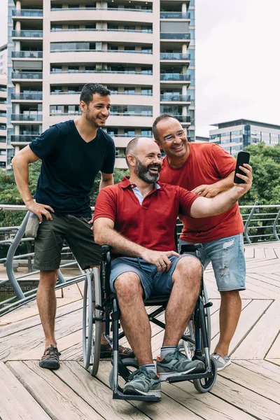 Man in wheelchair taking a selfie with two friends — Stock Photo, Image