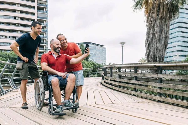 tekerlekli sandalyede adam iki arkadaş ile fotoğraf çekmek