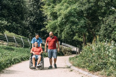 bakıcısı ve bir arkadaşı ile tekerlekli sandalyede adam