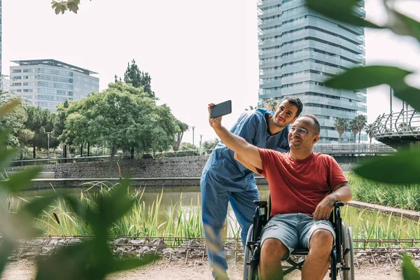 Людина в інвалідному візку робить фотографію зі своєю медсестрою — стокове фото