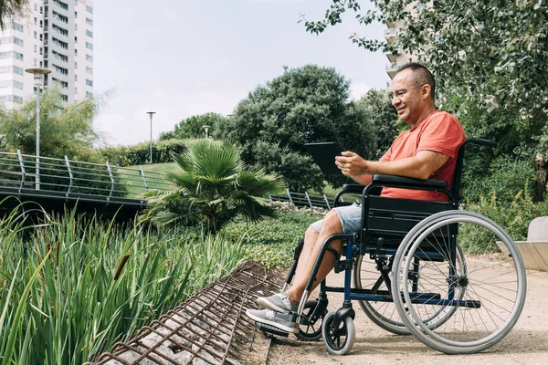 公園でタブレットで作業する障害者の男性 — ストック写真