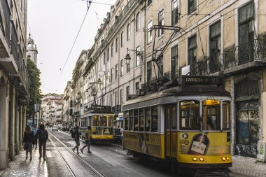 Sarı tramvaylar ve insanlar akşam karanlığında Lizbon sokaklarında