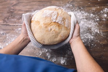 Elinde bir somun taze ekmek, evde sağlıklı beslenme kavramı olan tanınmamış bir insanın ellerine en iyi bakış açısı.