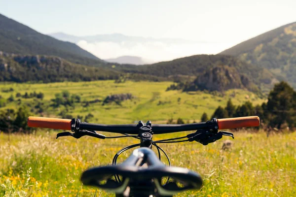 mountain bike in front of a green valley, focus on the handlebars, concept of sport and healthy lifestyle in nature, copy space for text