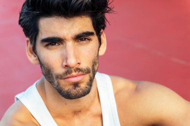 Kırmızı zeminde oturan yakışıklı bir sporcunun portresi, şehir sporu ve sağlıklı yaşam tarzı kavramı, metin için kopya alanı