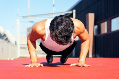 Kırmızı zeminde şınav çeken tanınmamış sporcu, şehir sporu ve sağlıklı yaşam tarzı kavramı