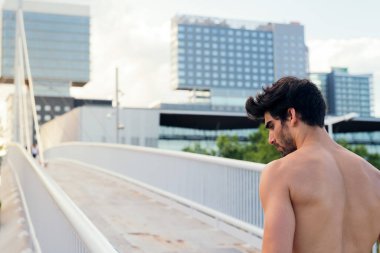 Binaların önündeki köprü, şehir sporu ve sağlıklı yaşam tarzı konsepti yanında yoğunlaşan üstsüz sporcu, metin için kopyalama alanı