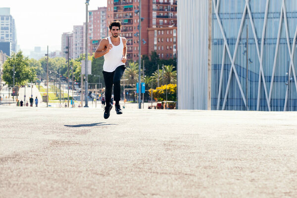 Front view of a runner running on the asphalt in the city, concept of urban sport and healthy lifestyle, copy space for text
