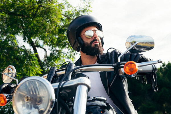 biker with helmet, mirror glasses and leather jacket riding his motorcycle, concept of freedom and rebellious lifestyle
