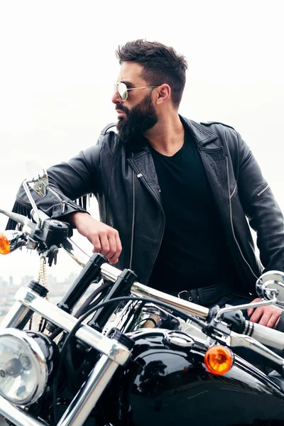Вертикальна Фотографія Чоловіка Шкіряною Курткою Сонцезахисними Окулярами Спираються Його Мотоцикл — стокове фото