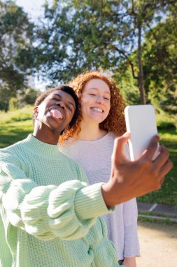 İki genç kadın şakalaşıyor ve parkta cep telefonuyla fotoğraf çekiyor. Bu arada birlikte vakit geçiriyorlar. Teknoloji kavramı ve arkadaşlar eğleniyor.