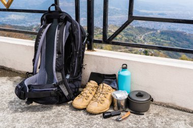 Trecking or hiking equipment - bagpack, boots, socks, folding knife, gas burner, water flask, kettle pot and flashlight. Outdoor activity concept. Still life close up stock photo. clipart