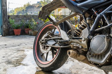 Motosikletin arka tekerine yakın çekim. Motosiklet evin yakınına park edilmiş. Stok fotoğrafı.
