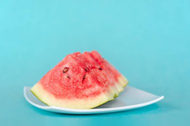 Mavi arka planda bir tabakta karpuz dilimleri. Lezzetli, taze yaz tatlısı. Stok fotoğrafı