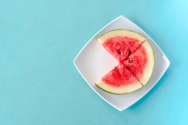 Mavi arka planda bir tabakta karpuz dilimleri. Lezzetli, taze yaz tatlısı. Kopyalama alanı ile üst görünüm. Stok fotoğrafı