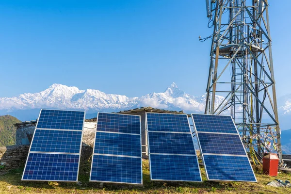 Solar panels near telecommunication tower in the mountain region. Snow covered mountain peaks on background. Green and environmentally friendly sources of energy. Stock photo