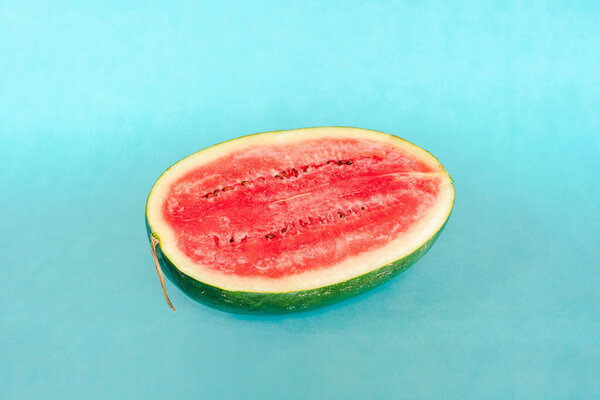 Half of fresh water melon on blue background. Fresh tasty summer dessert. Stock photo