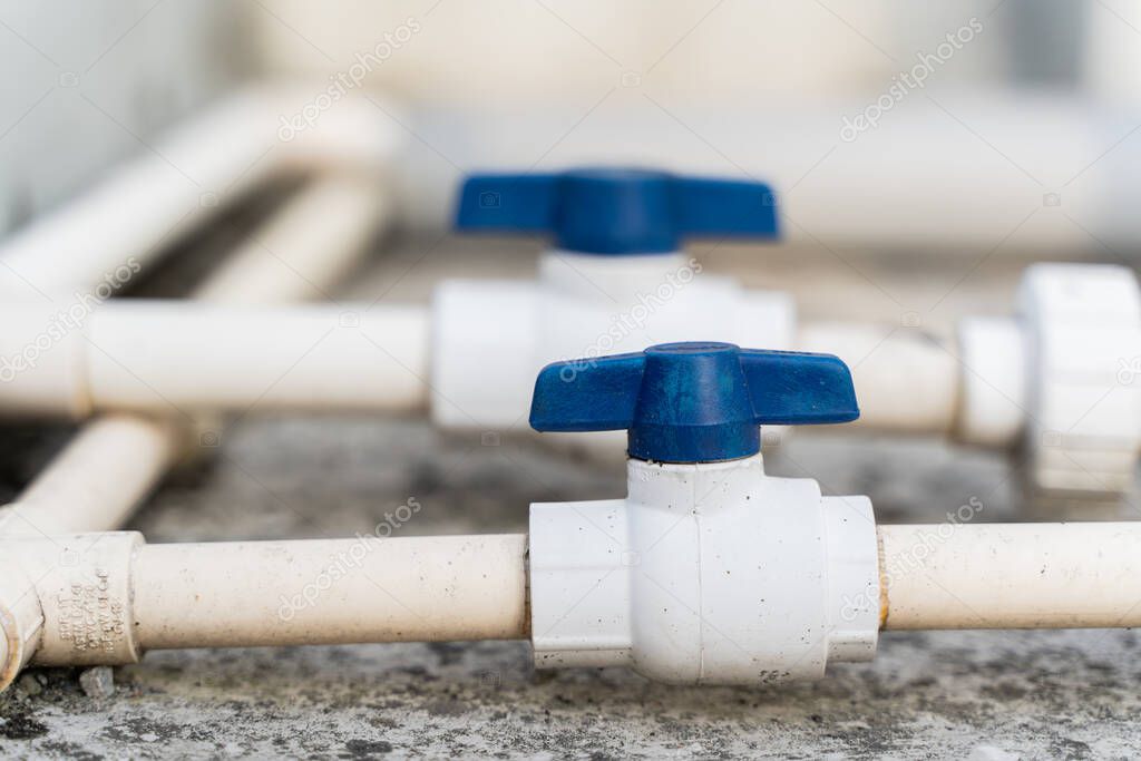 White plastic water pipes with blue faucet, parts of a home water supply system, close up stock photo