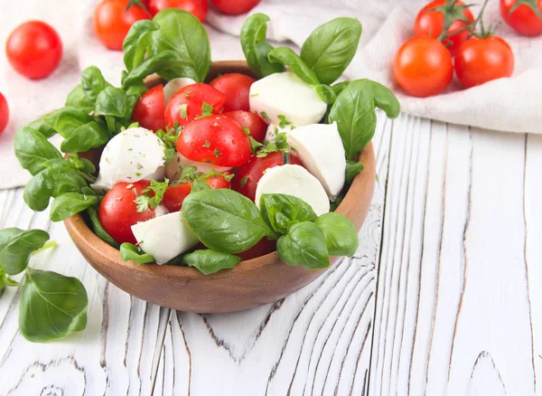 Fesleğenli ahşap arka plan üzerinde kırmızı kiraz domates ve mozzarella peynir