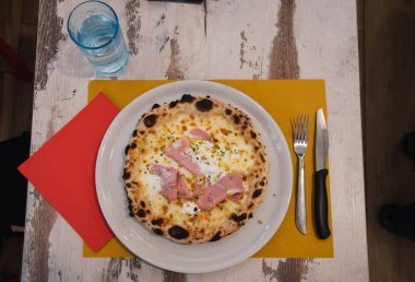 Torino restoranında bir masada jambonlu ve peynirli pizza.