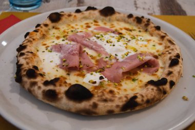 Torino restoranında bir masada jambonlu ve peynirli pizza.