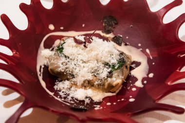 Lezzetli karidesli ravioli, kırmızı tabakta peynirli, bir restoranda çok güzel servis ediliyor.