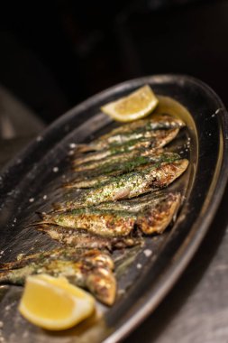 Maydanozlu ve limonlu ızgara sardalya bir restoranda servis edilmeye hazır.