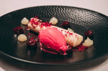 Lokantada servis edilen kırmızı meyveli dondurma ve marmelatlı peynir tatlısı.