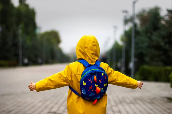 Sarı yağmurluklu bir çocuk ve boş bir şehirde sırt çantası. Kendini izole etme, salgın hastalık.