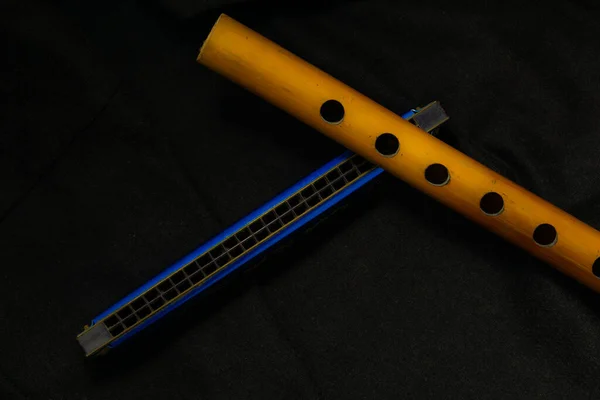 Musical instrument bamboo flute and harmonica placed on a dark background