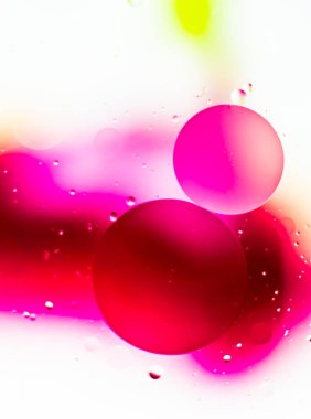 Su üzerindeki petrolün yakın plan görüntüsü ve pembe bir arka plan.