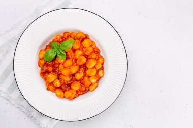 Gnocchi. Domates ve et soslu patates köftesi. İtalyan yemeği. Fesleğenle süslenmiş. Beyaz arka plan. Düz yatıyordu.