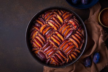 Erikli çikolatalı erik turtası ve geometrik erik süslemesi. Karanlık arka plan. Boşluğu kopyala.