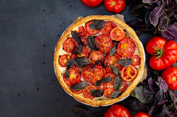 Tomato pie with red baisils, ricotta cheese, eggplants, orange zest. Dark background. Top view.