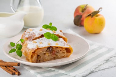 Kuru üzüm, fıstık ve tarçınlı alp elmalı turta. Güney Tyrol tarifi. Arka planda bir sürahi süt. Beyaz masada..