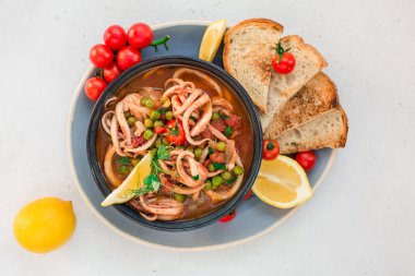 Domates ve bezelyeli kalamar, kabuklu ekmekle servis edilir. İtalyan mutfağı. Ev yapımı. Üst görünüm.