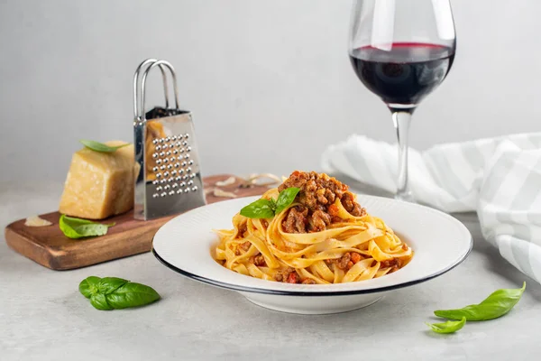 Kırmızı şaraplı İtalyan yemeği. Et, domates sosu ve parmesan peynirinden yapılmış bolonez soslu yumurtalı makarna tagliatelle. Açık gri arkaplan.