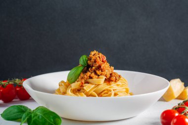 Tagliatelle ragu - İtalyan yumurtalı makarna et ve domates bolonez soslu. Beyaz masada ve siyah arka planda. Boşluğu kopyala.
