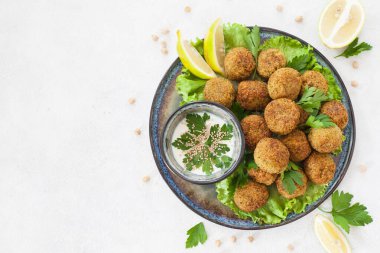 Falafel, bezelyeden yapılmış bol yağda kızartılmış bıldırcın, salata yatağının üzerine serilmiş. Beyaz arkaplan.