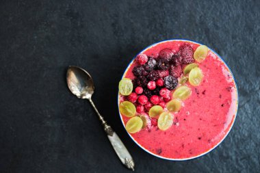 Kahvaltı Detoks Pink Smoothie muz ve orman meyveleri kase, koyu arka plan, üstten görünüm