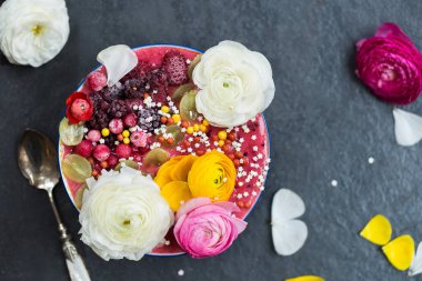 Kahvaltı Detoks Pink Smoothie muz ve orman meyveleri kase tepesinde Dondurulmuş çilek ve tipik çiçekler, koyu arka plan, üstten görünüm