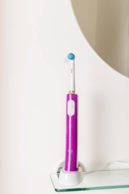 Açık renkli banyo raf üzerinde elektrikli şarj edilebilir diş fırçaları